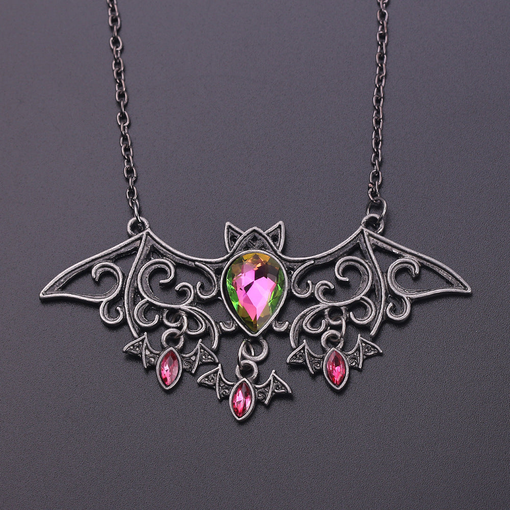 Bat-shaped necklace with a multicolored gemstone on a dark background