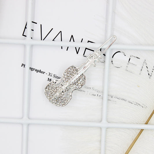 Silver guitar-shaped hairpin on a textured white surface
