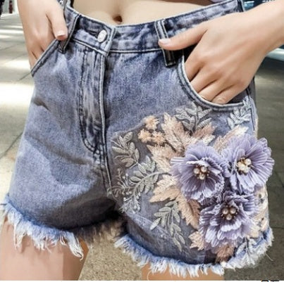 Denim shorts with floral embroidery and fringe details.