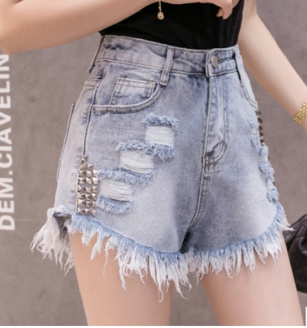 Denim shorts with studs and frayed edges on a neutral background
