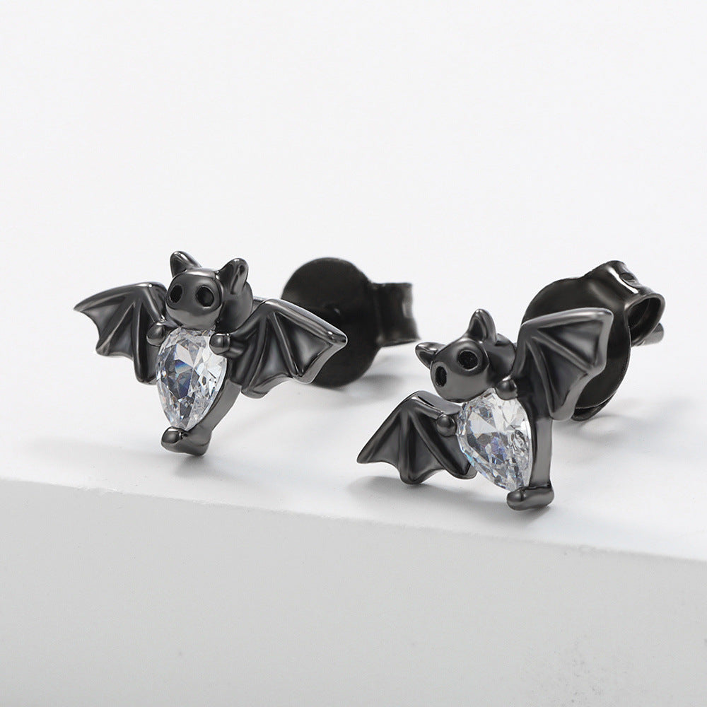 Black bat-shaped earrings with clear gemstones on a light gray background