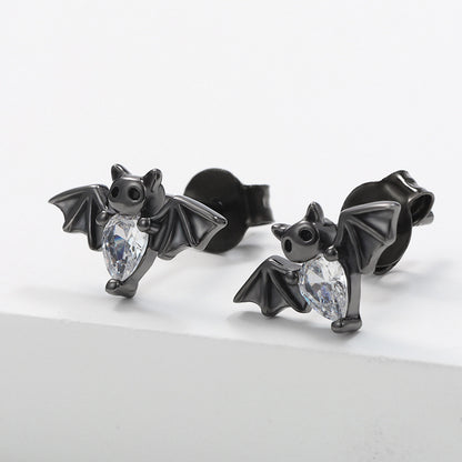 Black bat-shaped earrings with clear gemstones on a light gray background