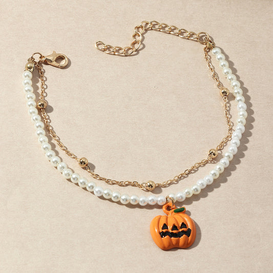 Two-layered bracelet with pearl beads and a Halloween pumpkin charm on a beige background