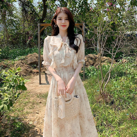 Woman in a floral dress holding a woven bag in a garden setting