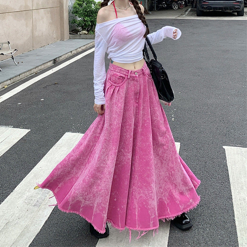 Person wearing a white off-shoulder top and pink skirt on a street.