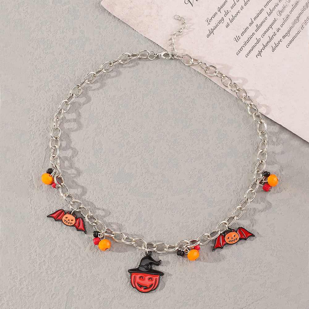 Halloween-themed charm bracelet on a light gray surface with a magazine underneath.