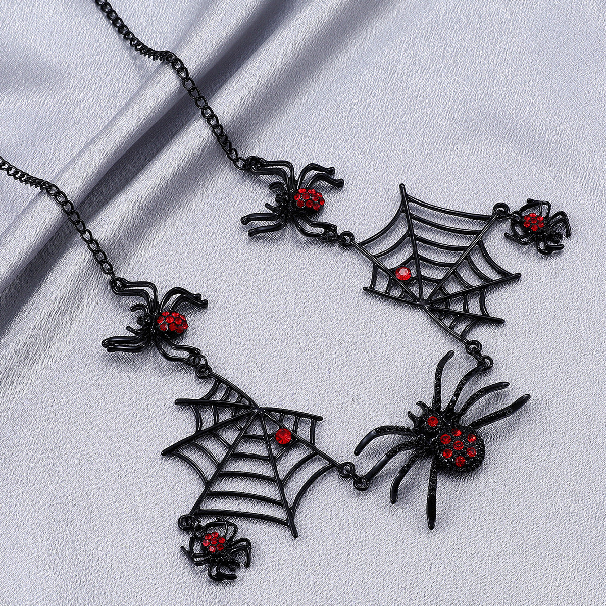 Black spider and web necklace with red accents on a light gray background