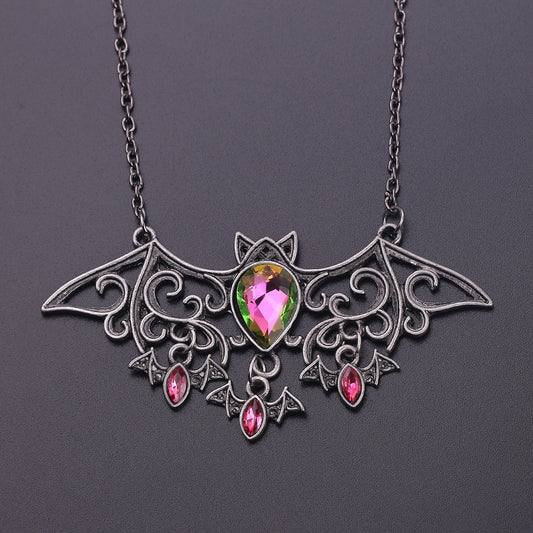 Bat-shaped necklace with a multicolored gemstone on a dark background