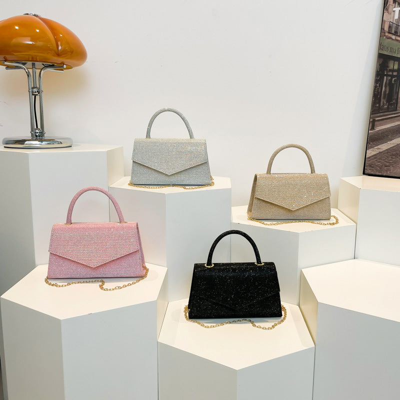 Four handbags displayed on white cubes with a lamp and picture frame in the background.