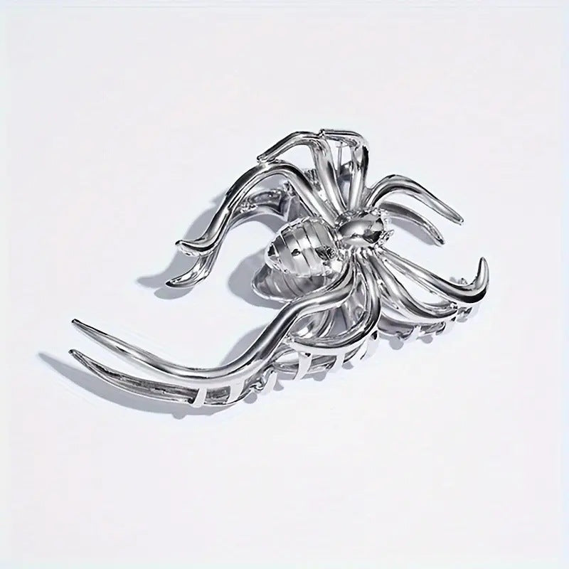 Silver spider-shaped brooch on a light gray background