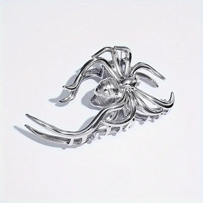 Silver spider-shaped brooch on a light gray background