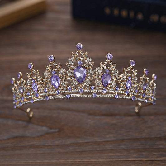 Gold tiara with purple gemstones on a wooden surface