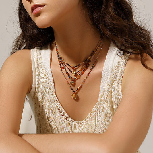 Close-up of a woman wearing multiple necklaces with a neutral background